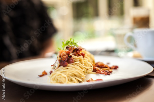 spaghetti becon on white disc in resturant
