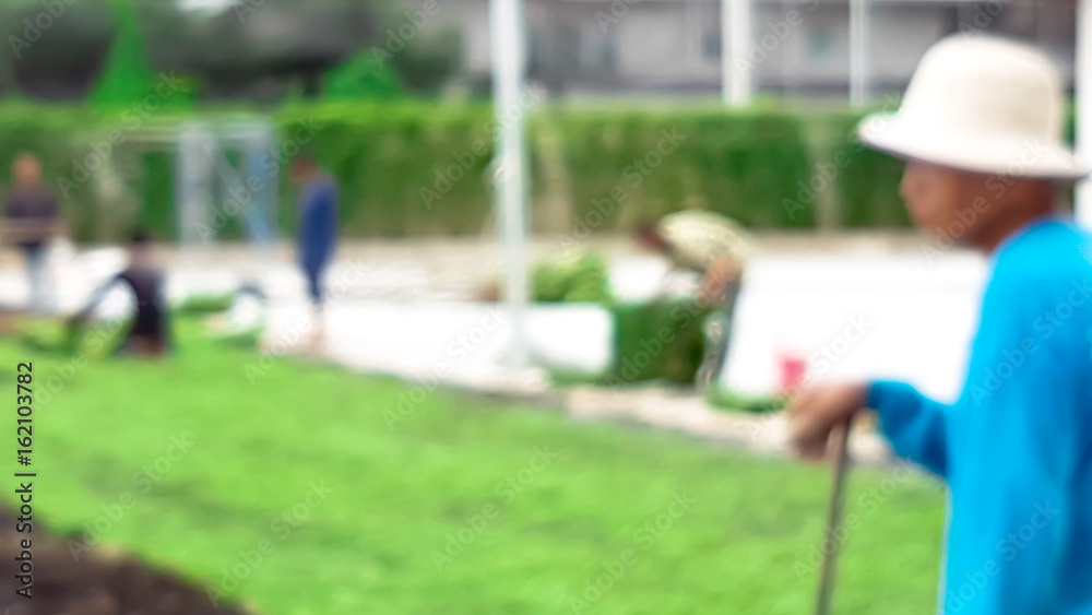 Blur of gardener in process of grass arrangement