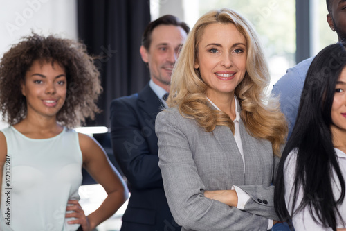 Businesswoman Leading Businesspeople Group In Modern Office Smiling, Female Boss Over Business People Team Stand Folded Hands With Successful Mix Race Colleagues