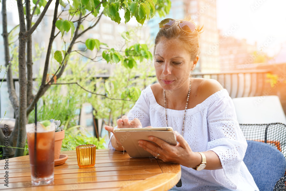 Woman on rooftop websurfing on digital tablet Woman on rooftop websurfing on digital tablet