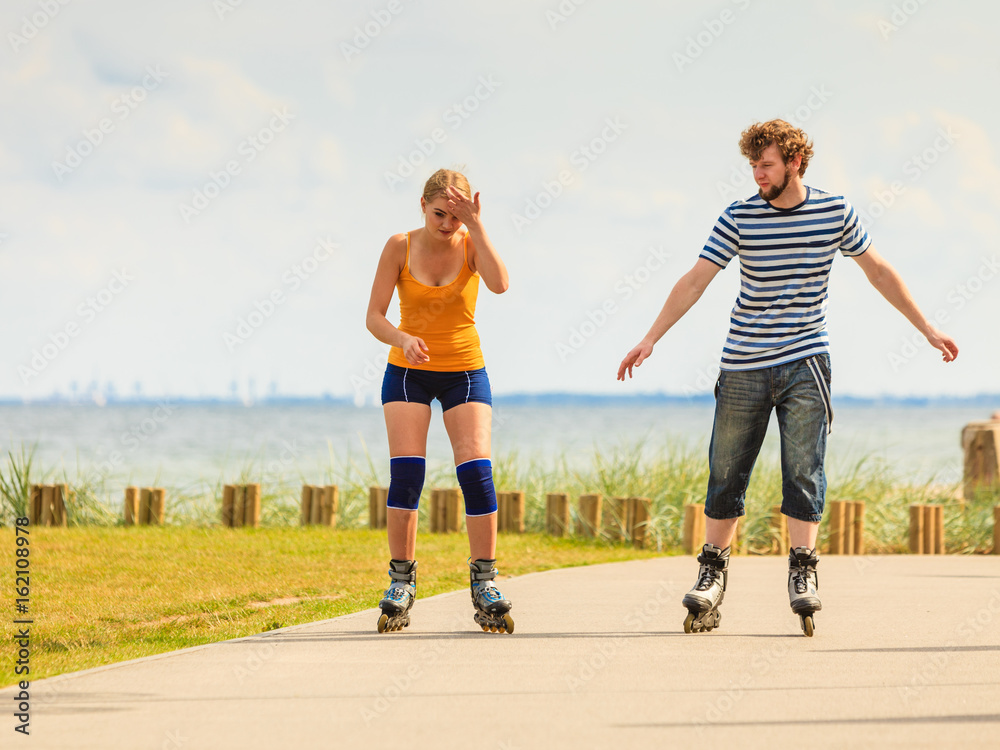 Fototapeta premium Young couple on roller skates riding outdoors