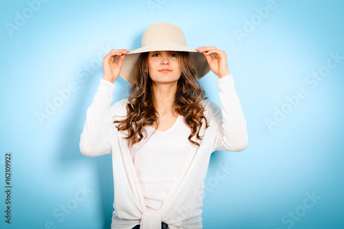 Feminine womam looking camera, fashion, straw hat, outfit, clothes, figure,look on blue background photo