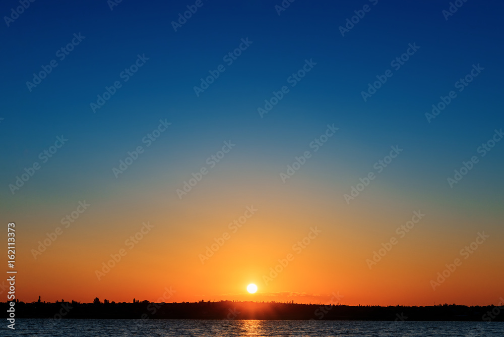 orange sunrise over river in blue sky