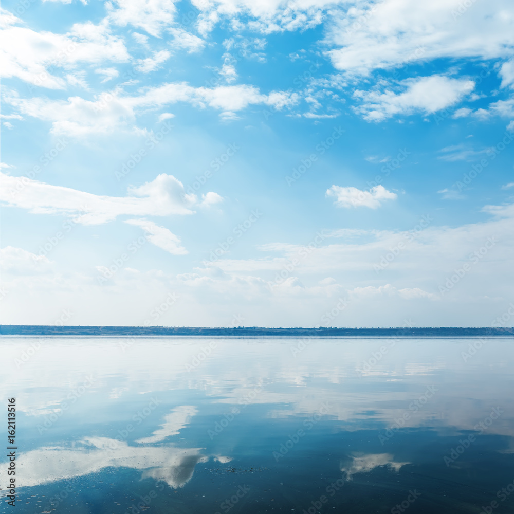 Fototapeta premium deep blue sky with clouds over river and reflection of it