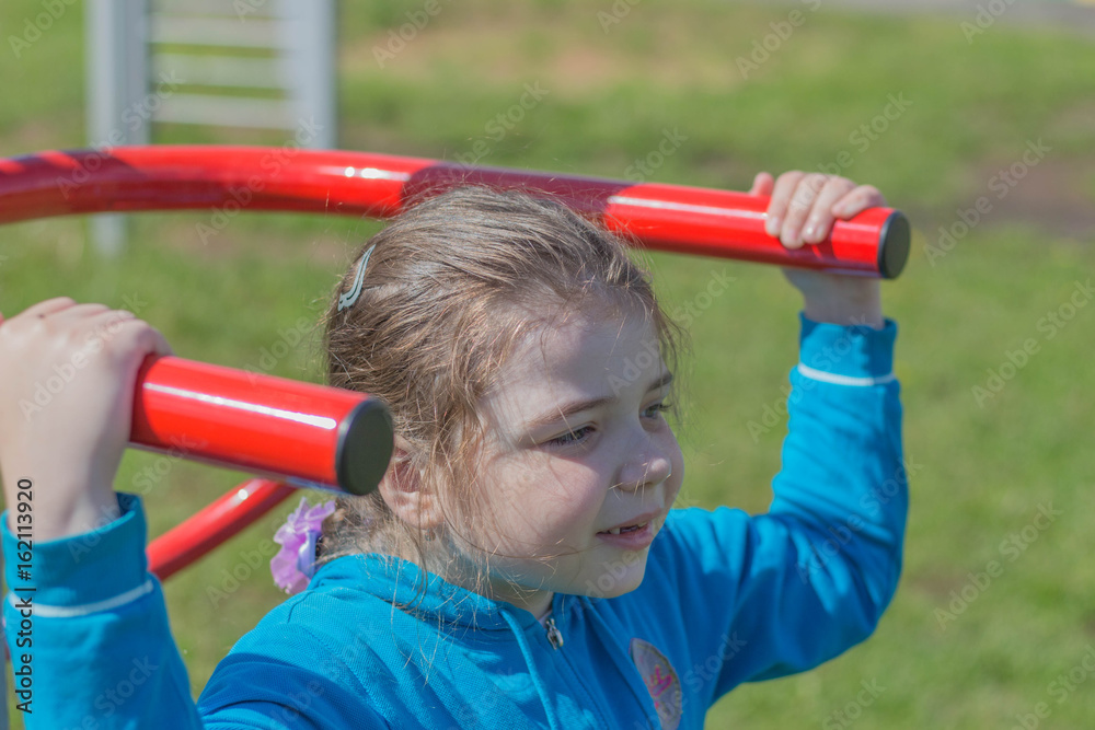 Obraz premium Девочка выполняет упражнения на спортивных снарядах