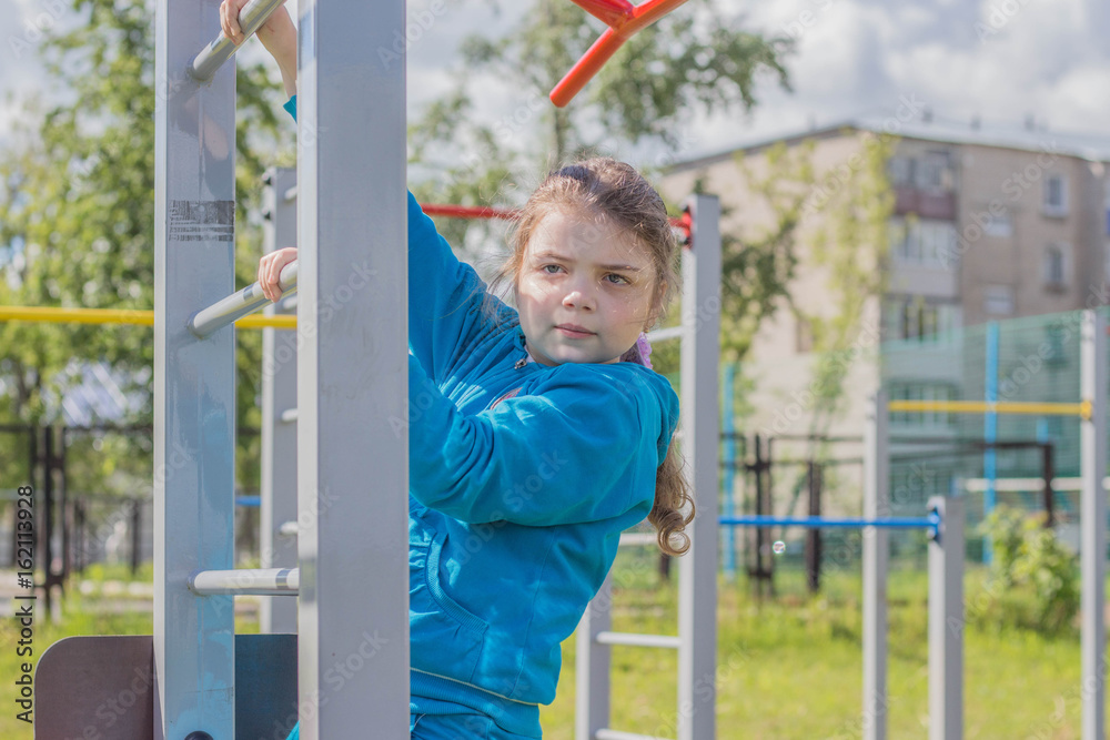 Obraz premium Девочка выполняет упражнения на спортивных снарядах