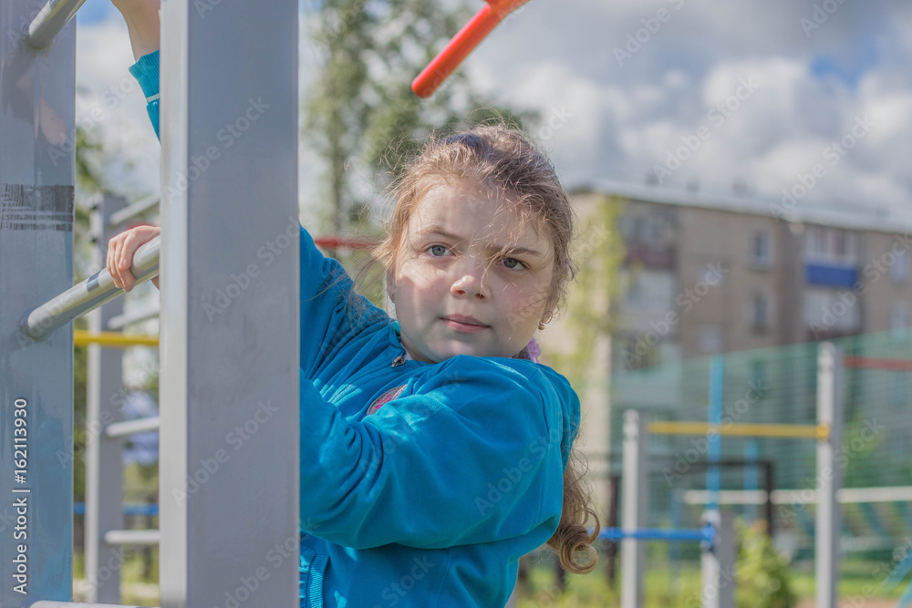 Obraz premium Девочка выполняет упражнения на спортивных снарядах
