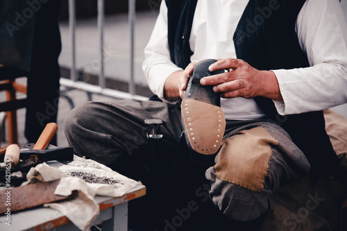 Master tailor makes shoes from leather. Concept of the old customs of making shoes and shoes.