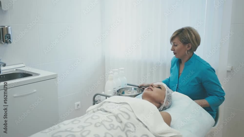 Employee of the spa salon prepares a cream for applying to the face of a young girl in room Employee of the spa salon prepares a cream for applying to the face of a young girl in room