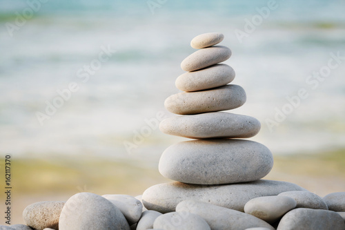 Stack of white pebbles stone against sea background for spa  balance  meditation and zen theme.