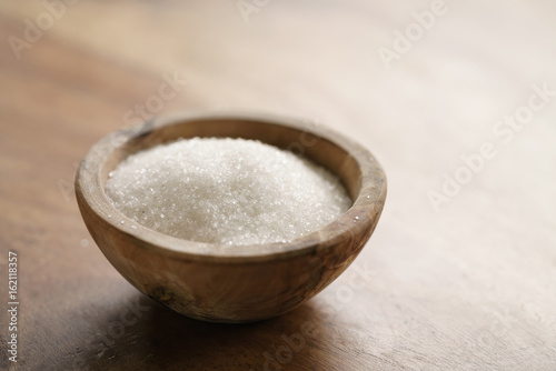 white sugar in wood bowl on wooden table photo