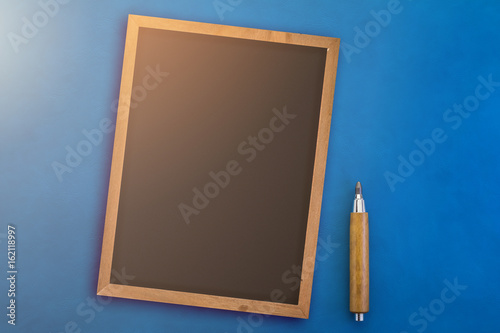 black chalkboard with wooden pencil on blue color leather background with free copyspace for your creativity ideas text