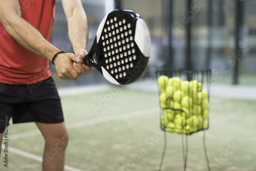 Man training in paddle tennis class with basket balls photo