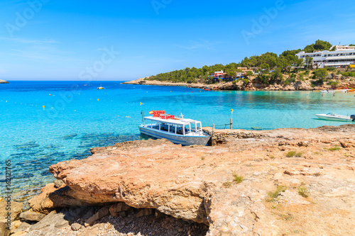 White and blue colour ferry boat for tourists mooring in Cala Portinatx bay, Ibiza island, Spain © pkazmierczak