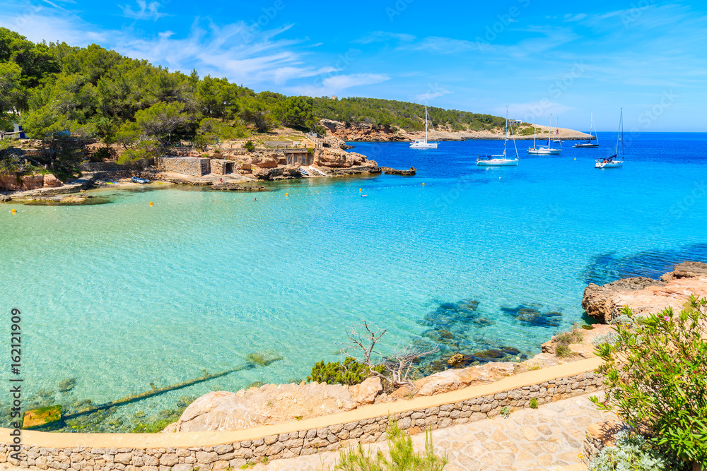 View of Cala Portinatx beach and coastal promenade, Ibiza island, Spain
