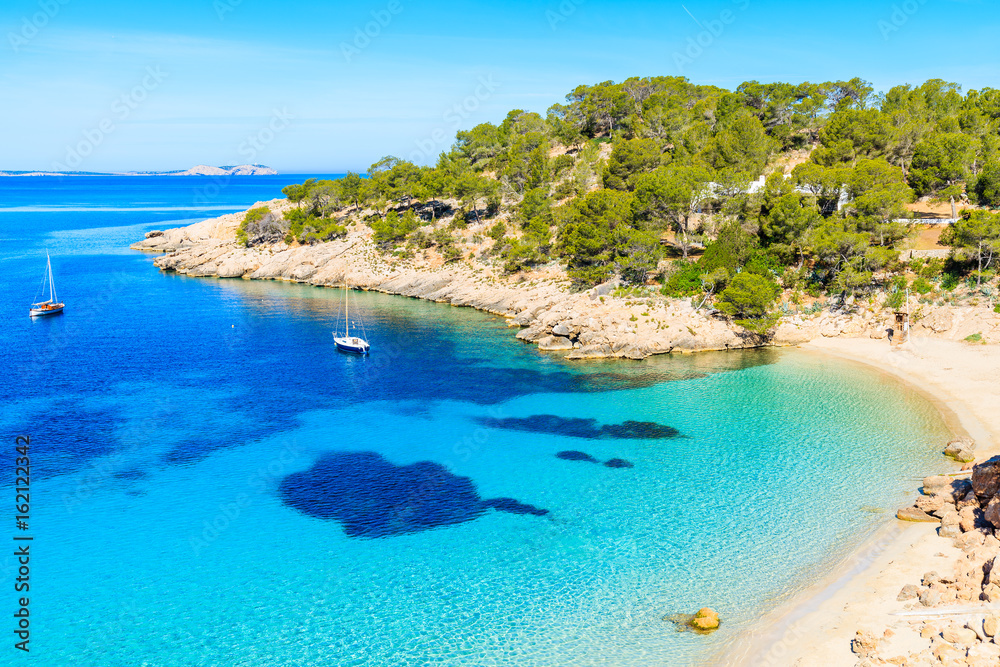 View of beautiful beach in Cala Salada famous for its azure crystal clear sea water, Ibiza island, Spain View of beautiful beach in Cala Salada famous for its azure crystal clear sea water, Ibiza island, Spain
