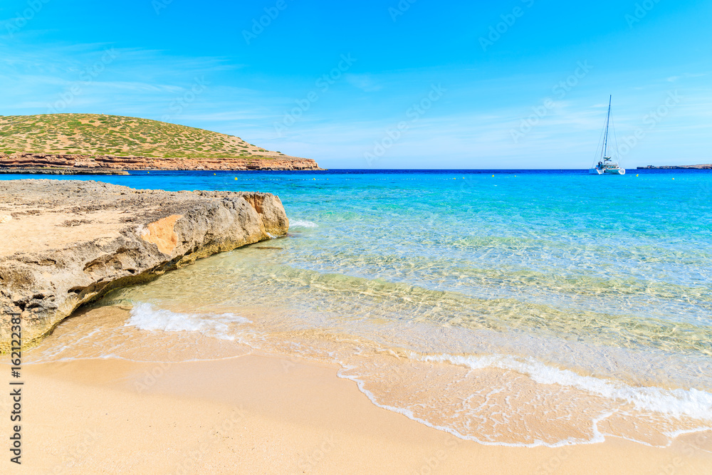 Beautiful sandy Cala Comte beach and catamaran boat on sea, Ibiza island, Spain