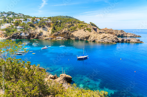 Fishing and sailing boats on blue sea water in Cala Vadella bay, Ibiza island, Spain