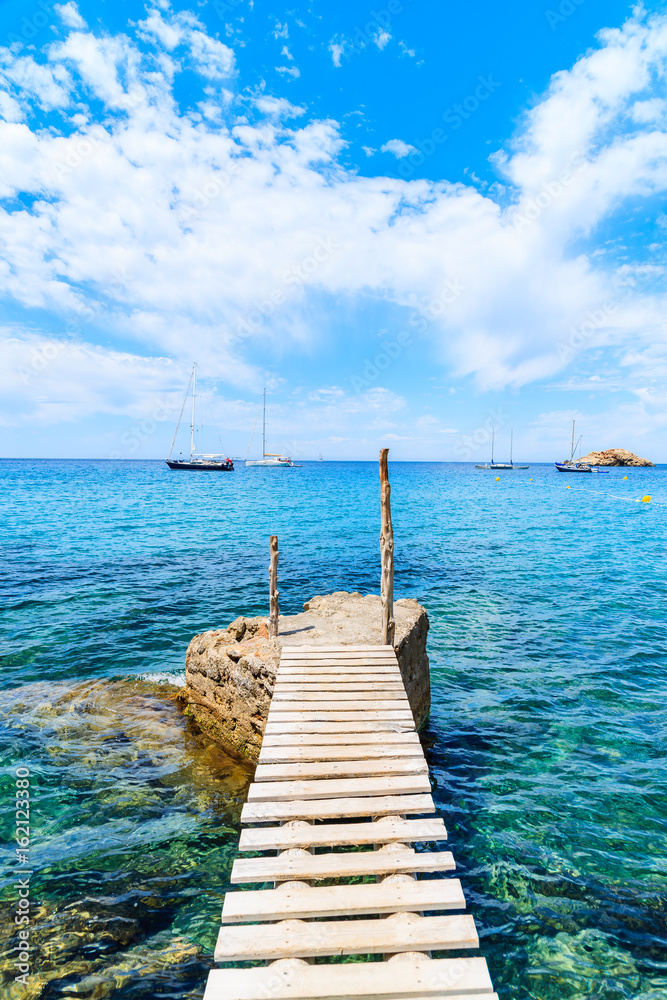 Small wooden pier in Cala d'Hort bay and view of Es Vedra island, Ibiza island, Spain Small wooden pier in Cala d'Hort bay and view of Es Vedra island, Ibiza island, Spain