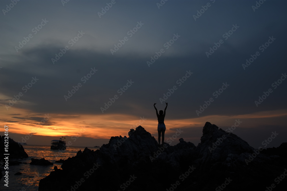 silhouette of woman watching warm sunset with seaside