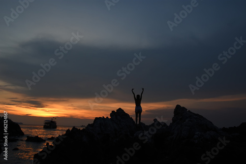 silhouette of woman watching warm sunset with seaside