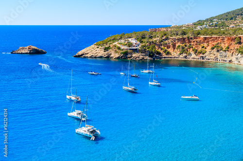 View of Cala d'Hort bay with sailing boats on beautiful azure blue sea water, Ibiza island, Spain