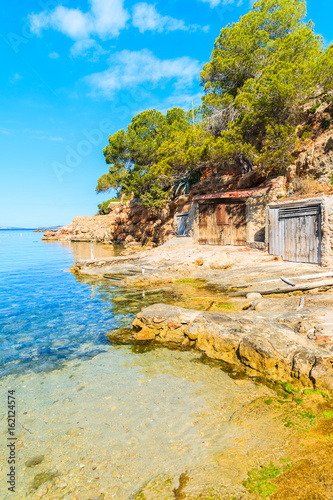 View of beautiful Cala Gracio beach with boat houses on shore at early morning, Ibiza island, Spain photo