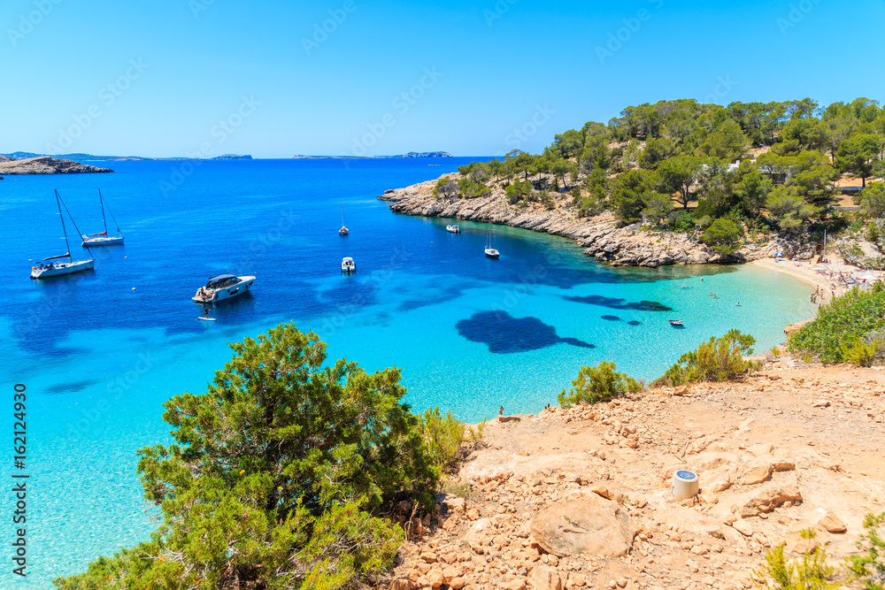 View of beautiful beach in Cala Salada bay famous for its azure crystal clear sea water, Ibiza island, Spain