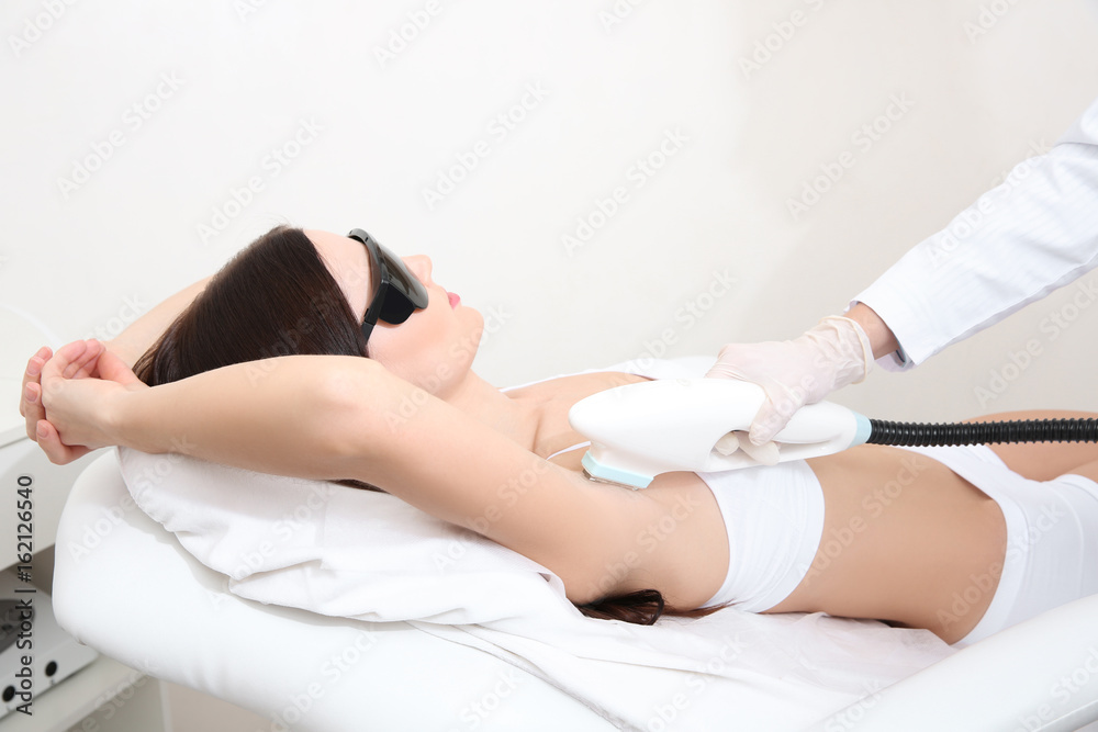 Fototapeta premium Beautiful woman getting laser epilation in beauty salon