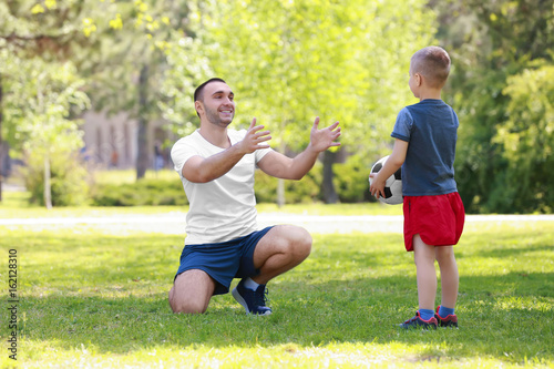 Father and son playing on green grass in park