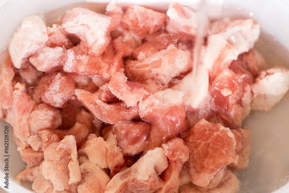 Raw pork meat in water, washing cleaning for cooking.