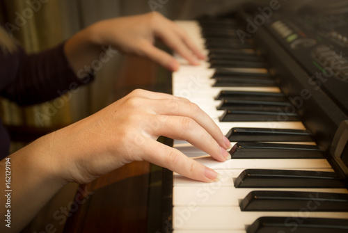 Closeup image of female hands playing on piano