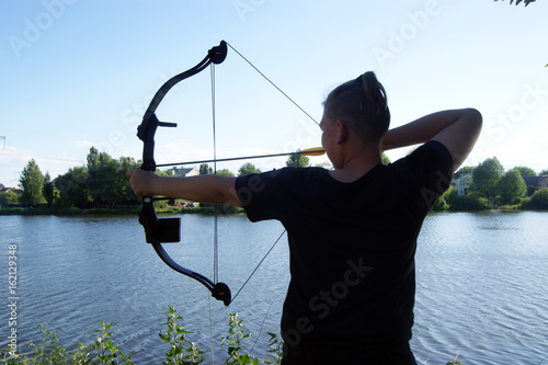 Bow and arrows, hunting by the river, young blue-eyed hunter.