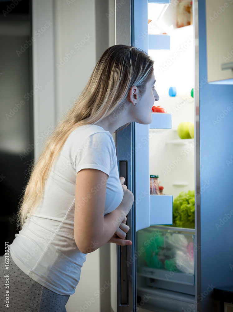 Woman looking inside the refrigerator for something to eat at late night Woman looking inside the refrigerator for something to eat at late night