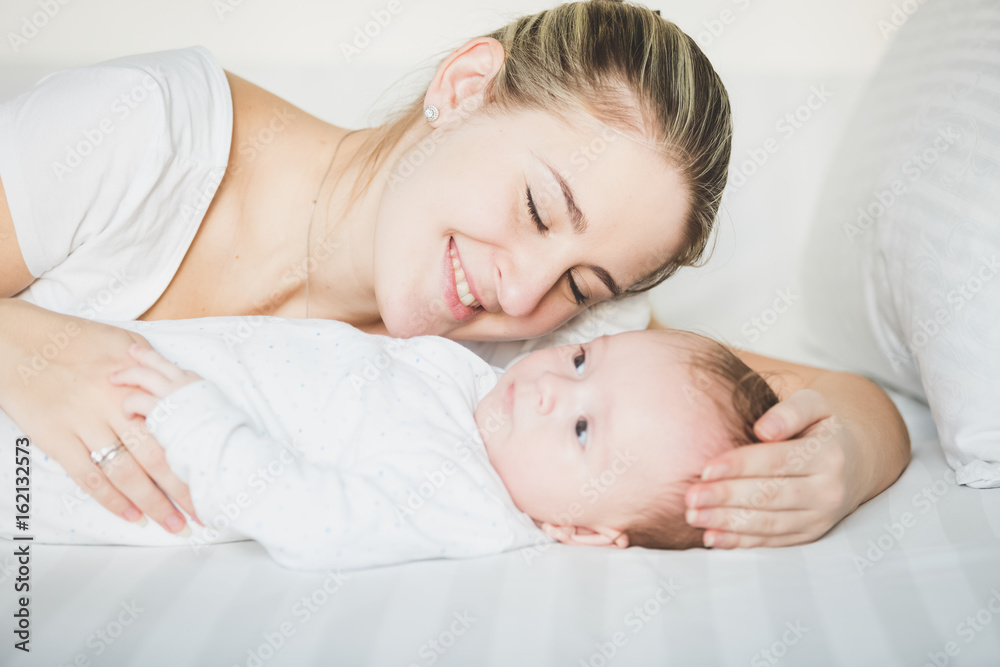 Portrait of smiling mother lying with 3 months old baby on bed Portrait of smiling mother lying with 3 months old baby on bed