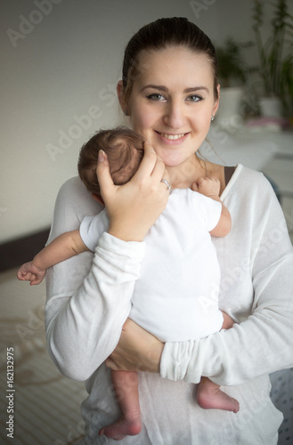 Portrait of smiling caring mother holding cute baby boy on hands