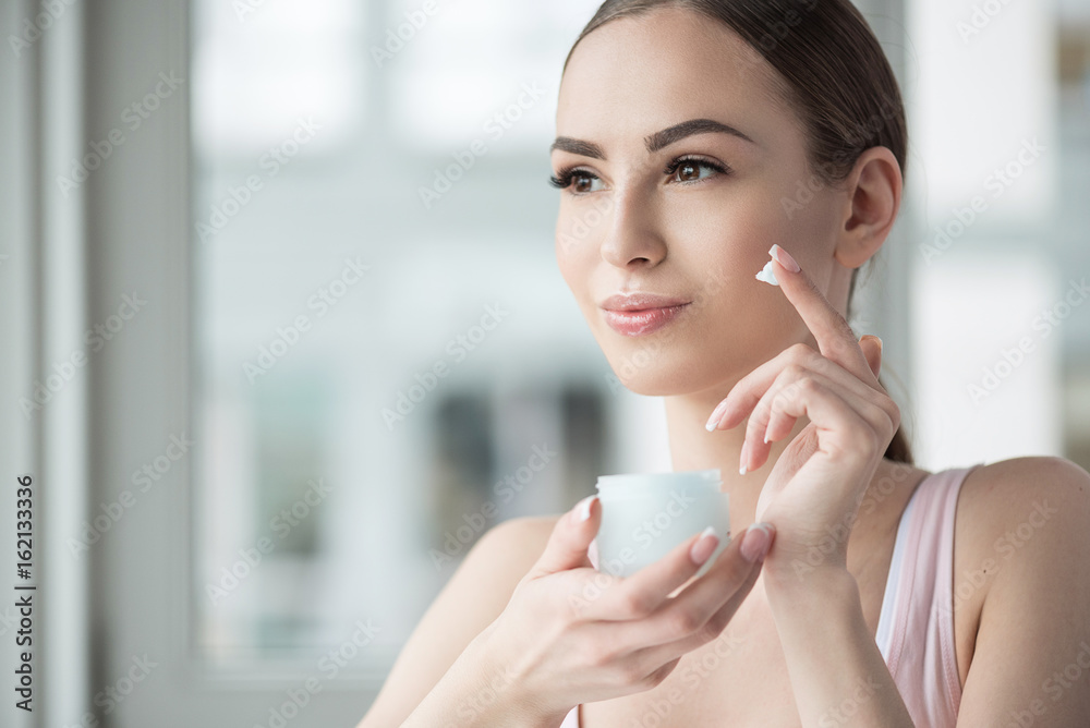 Happy youthful woman using facial cosmetics Happy youthful woman using facial cosmetics