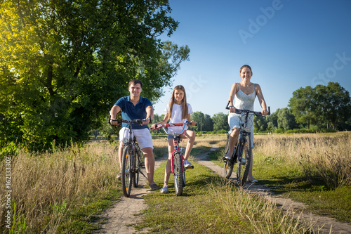 Happy family with daughter having weekend on their bicycles