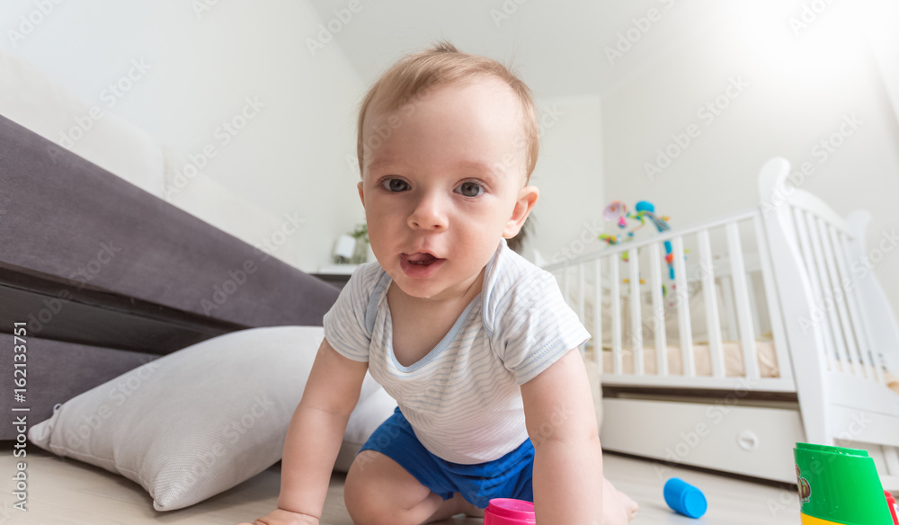 Happy cheerful baby boy playing on floor and looking at camera Happy cheerful baby boy playing on floor and looking at camera