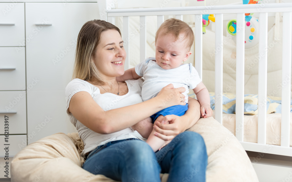 Cheerful young mother reading book to her baby boy at living room Cheerful young mother reading book to her baby boy at living room
