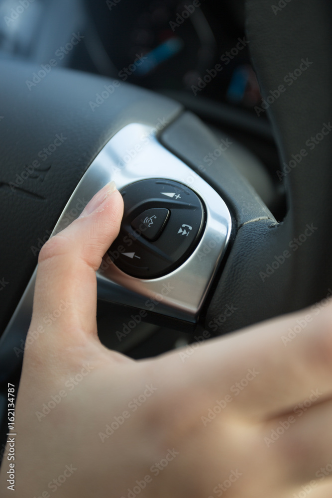 Closeup of driver using control panel on steering wheel