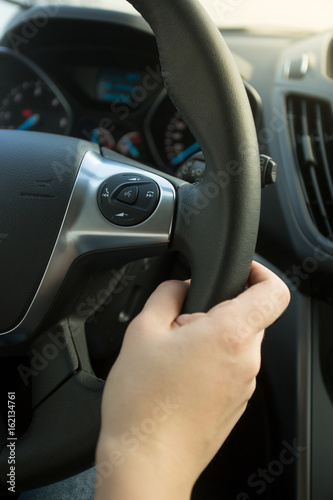 Closeup photo of woman holding leather steering wheel