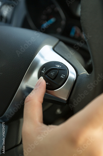 Closeup of driver pressing phone button on car steering wheel