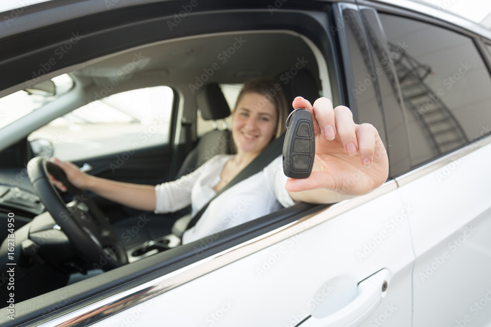 Closeup of female driver showing keys through open window of car