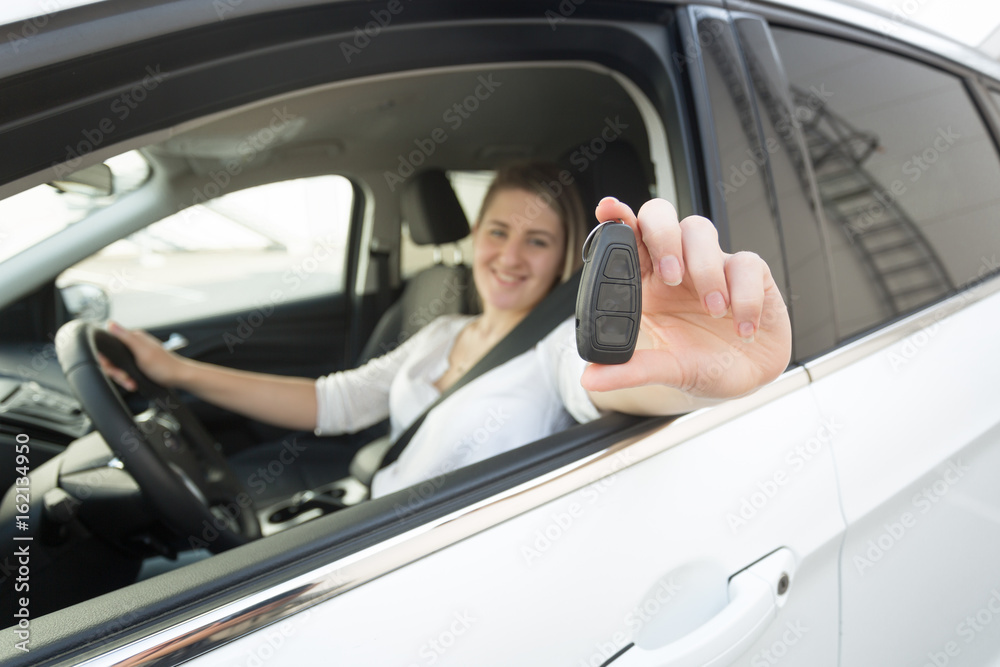 Closeup of female driver showing keys through open window of car Closeup of female driver showing keys through open window of car