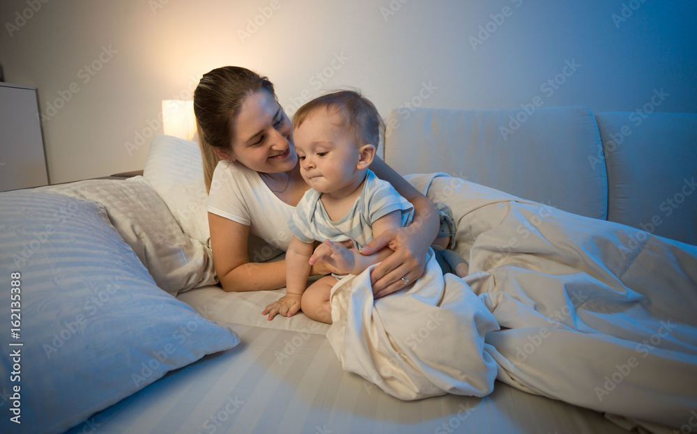 Cute baby boy and his mother in bed at late night Cute baby boy and his mother in bed at late night