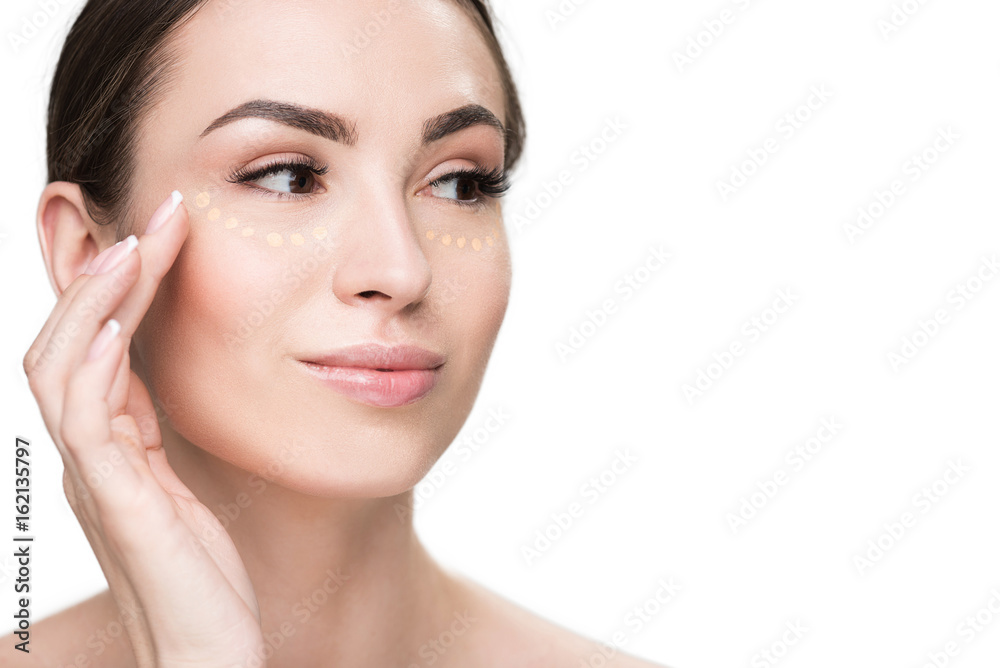 Cheerful young lady using concealer