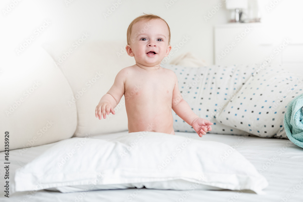 Smiling baby boy playing on bed with big pillow Smiling baby boy playing on bed with big pillow