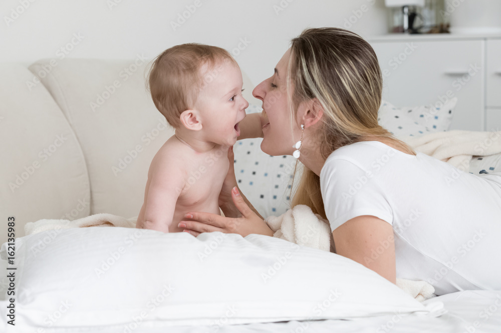 Portrait of cheerful baby with mother lying on big white pillow Portrait of cheerful baby with mother lying on big white pillow