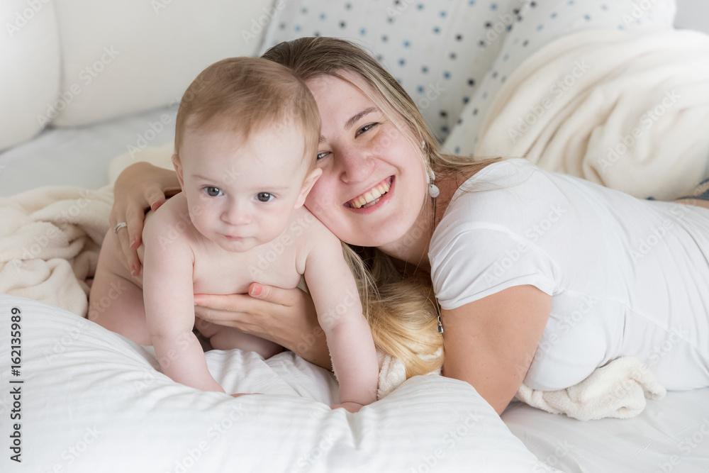 Happy young mother lying on big pillow with her 9 months old baby Happy young mother lying on big pillow with her 9 months old baby